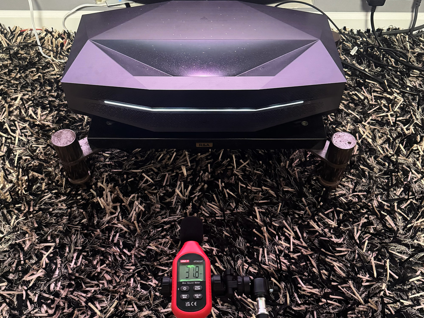 A UNI-T UT353 BT sound level meter in front of the projector reading 37.8 dB