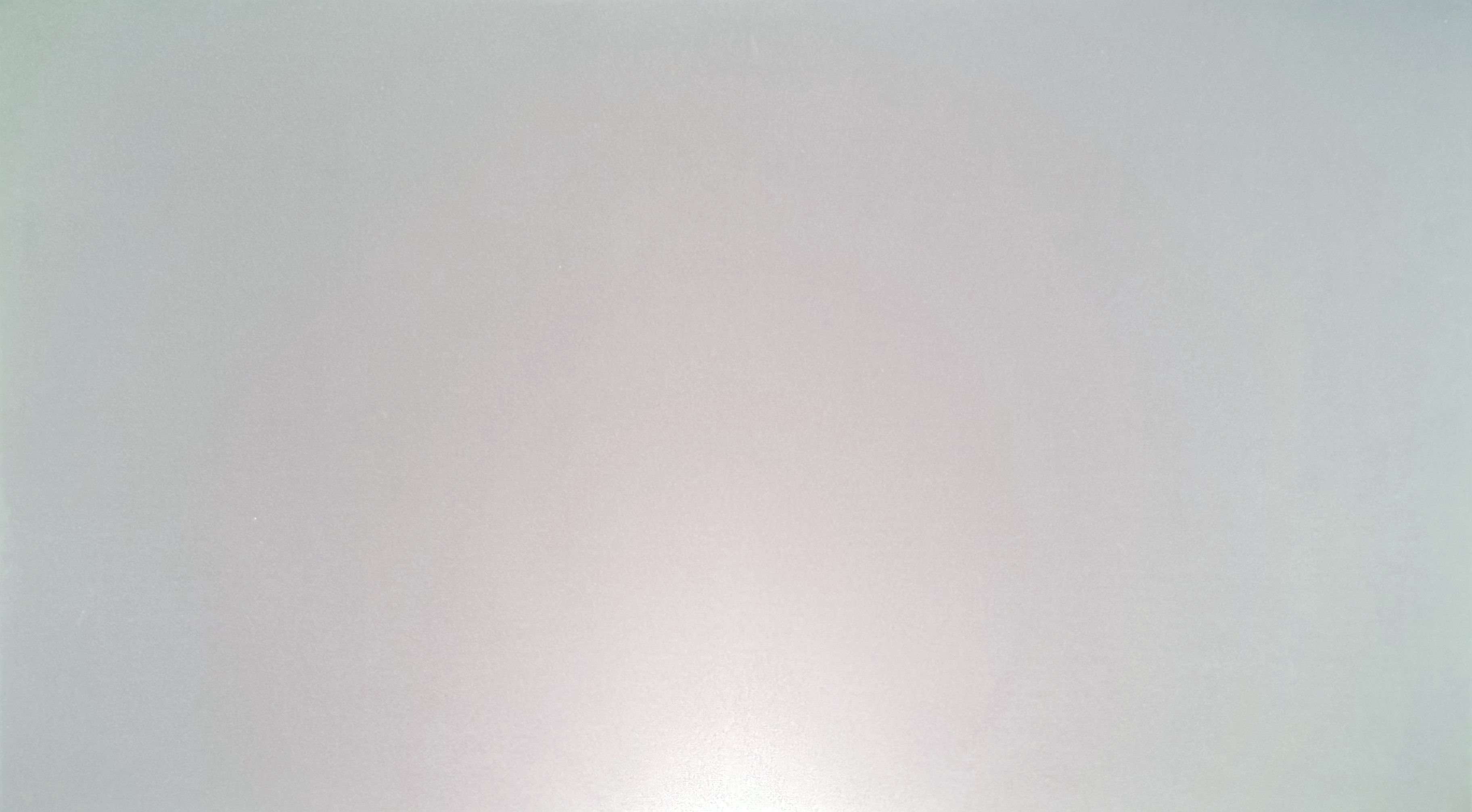 Full white field on the screen: a warm patch in the lower center and a greenish tint along the top and in the corners